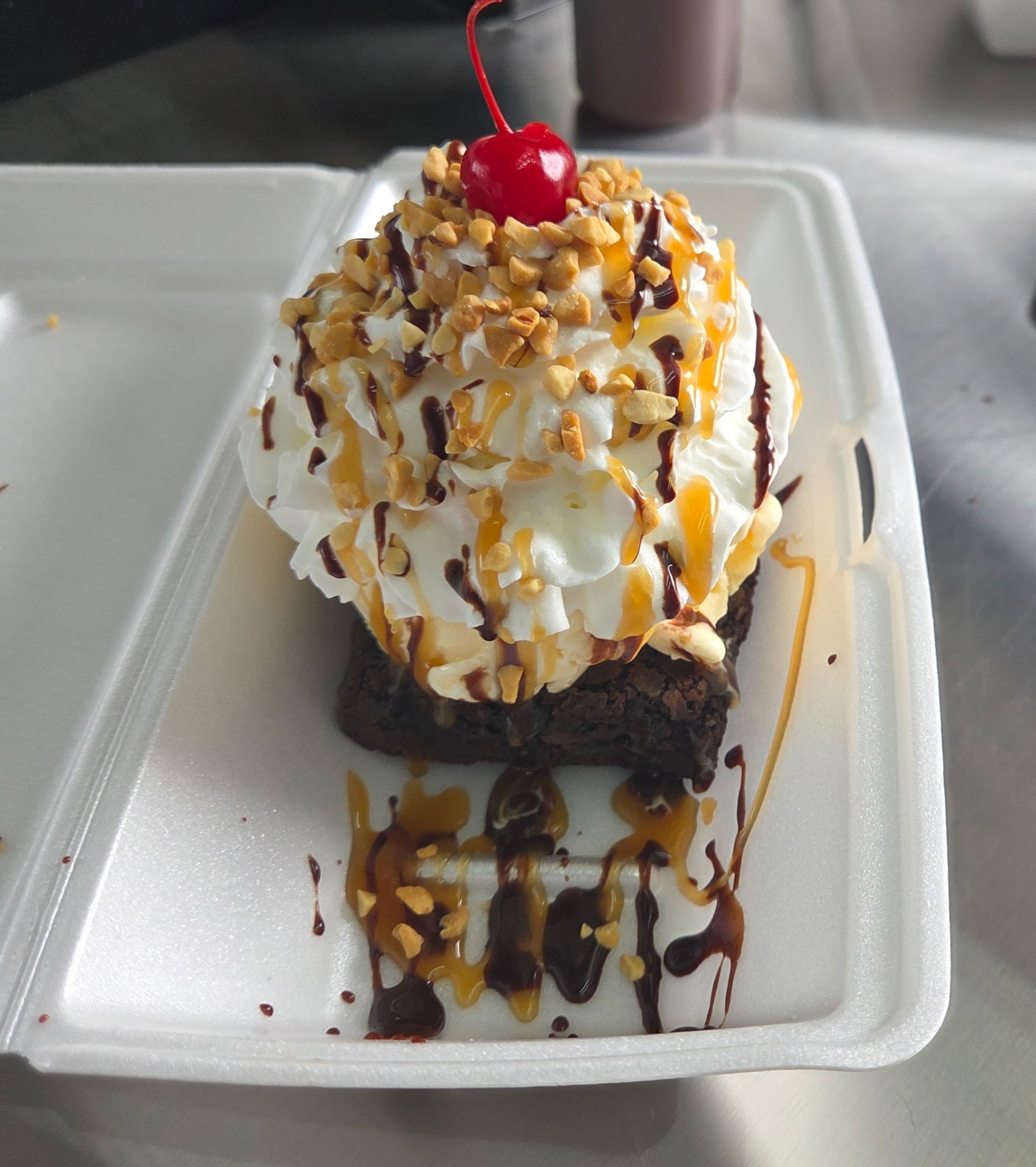 Brownie sundae with whipped cream, caramel, hot fudge, nuts and a cherry