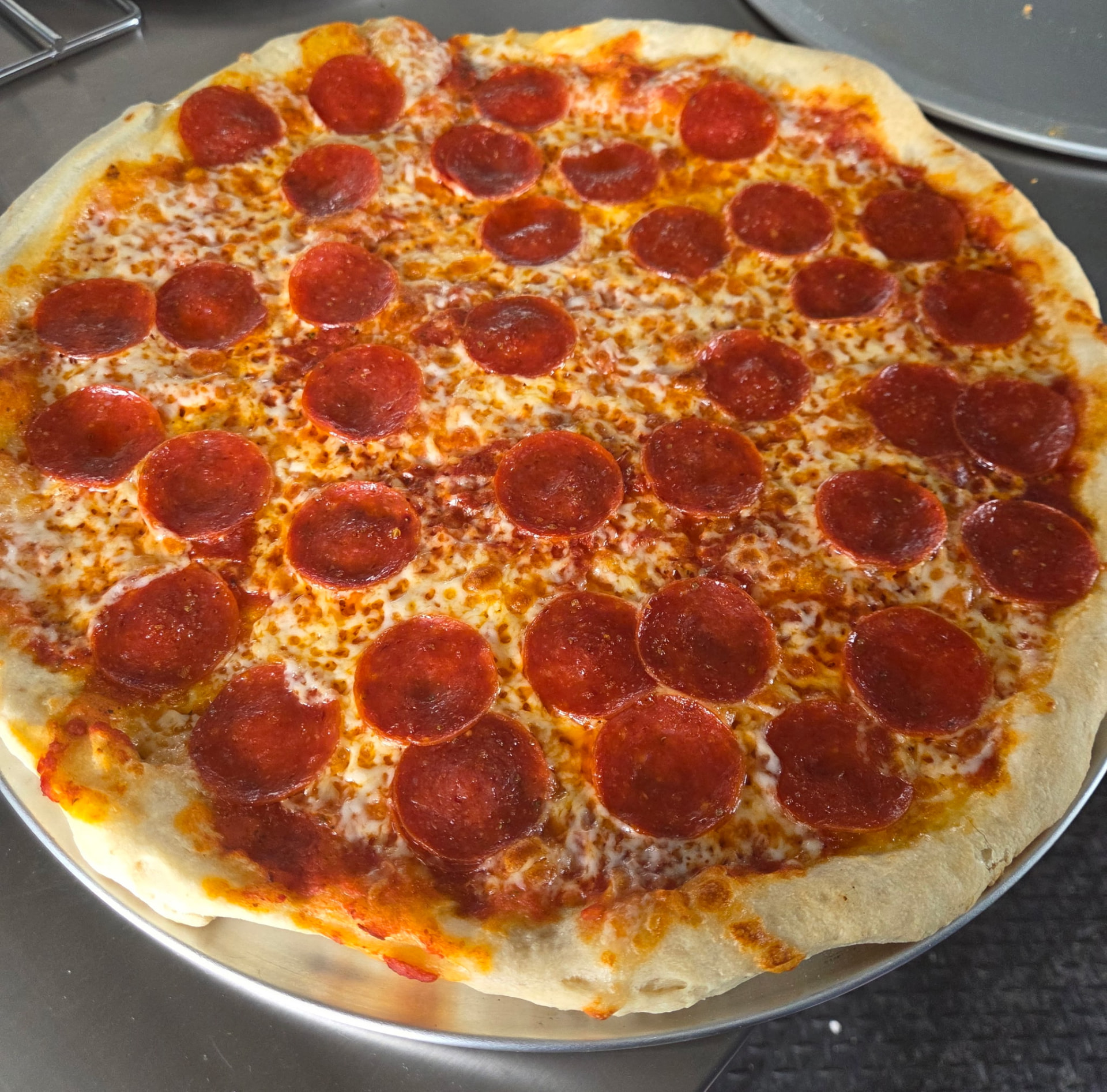 A fresh hand-tossed pepperoni pizza on the pan